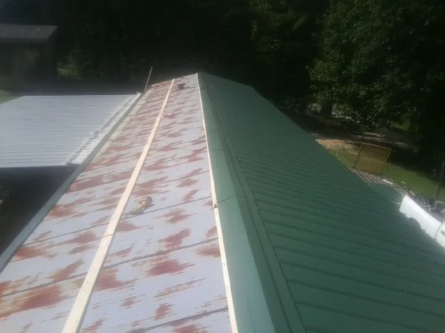 Old rusted panels beside newly installed green metal roofing — Wind Damage Roof Repair by Roofing Brothers in Far Rockaway