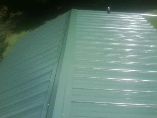 New green metal panels meeting at the ridge of a roof — Flat Roof Repair work by our crew in Far Rockaway