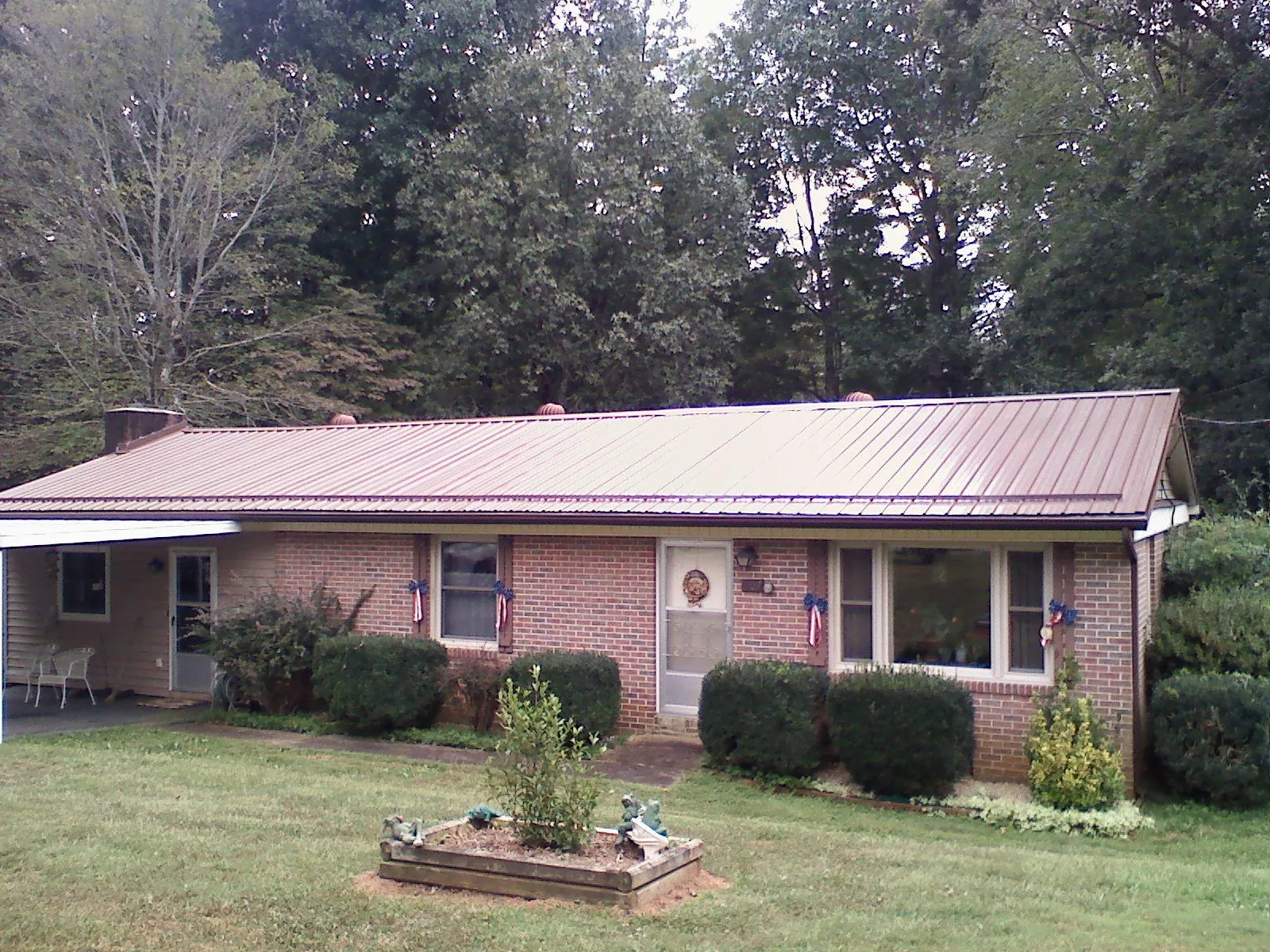 Bronze metal roof on a brick ranch home with a carport in Far Rockaway