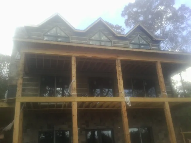 Dormers and porch framing on a large log home under construction — Roof Coating work by our crew in Far Rockaway