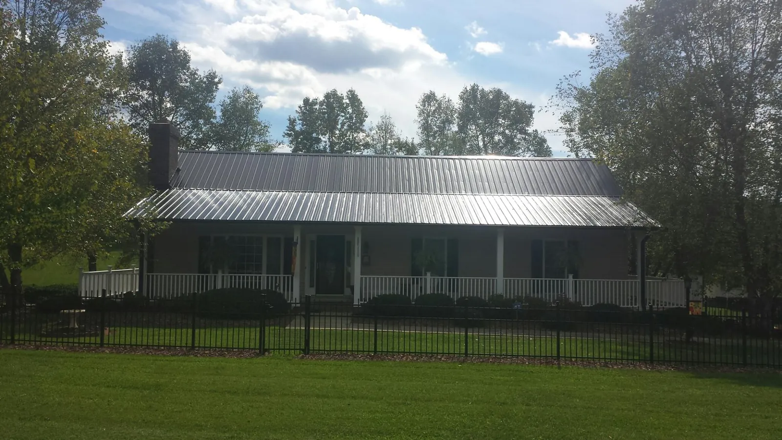 Gray metal roof on a brick ranch with a full width front porch — Gutter Guard Installation work by our crew in Far Rockaway
