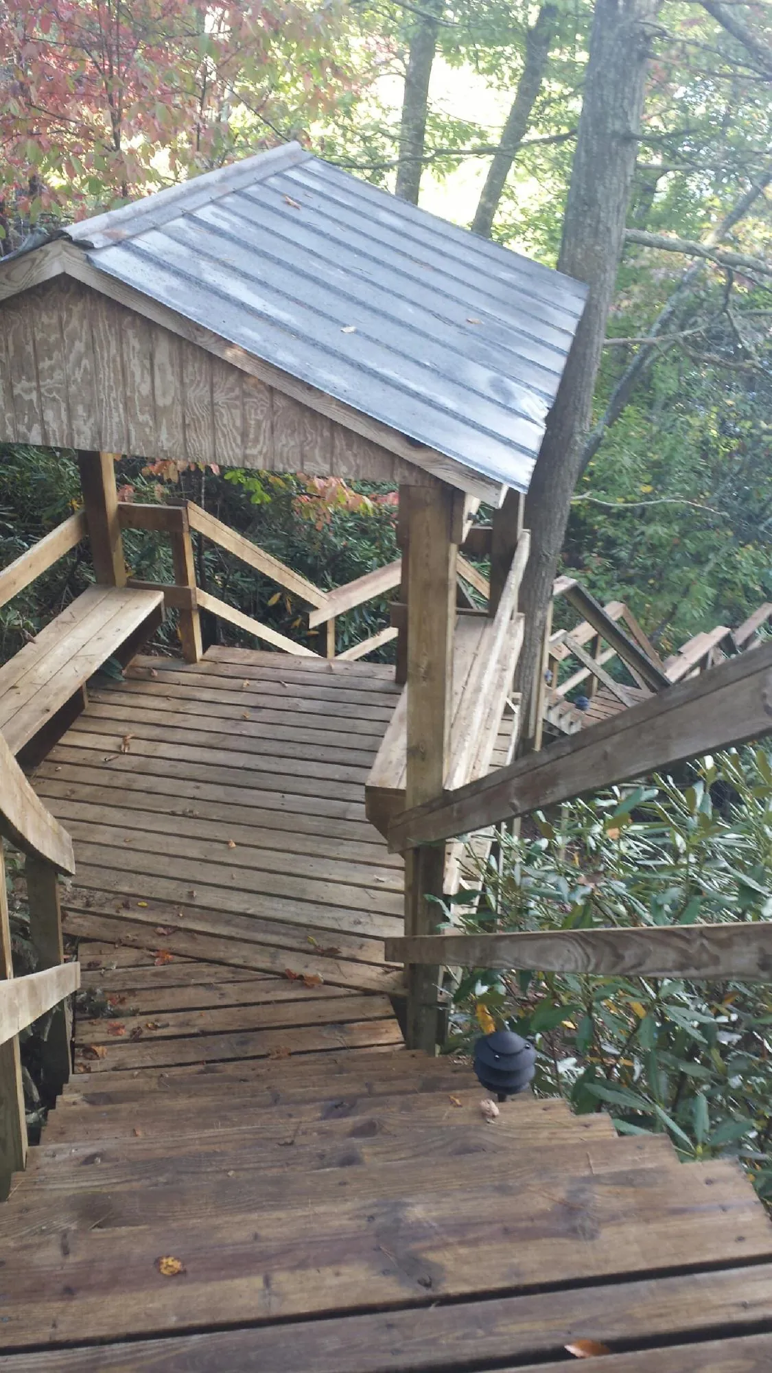Metal roofed shelter over wooden steps on a wooded walkway — Skylight Repair & Installation work by our crew in Far Rockaway