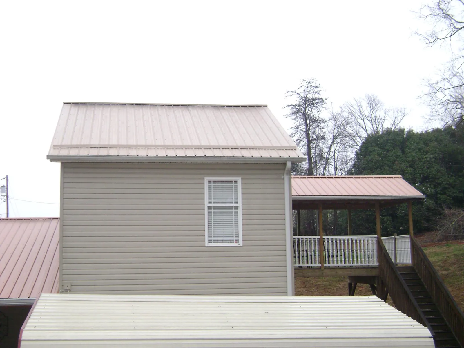 Tan metal roofs on a two story addition and attached porch, from a Roof Replacement job in Far Rockaway