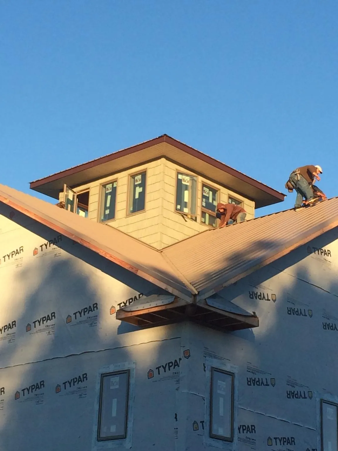Roofers working around a rooftop cupola on a new metal roof at sunset — Roof Waterproofing in Far Rockaway by Roofing Brothers